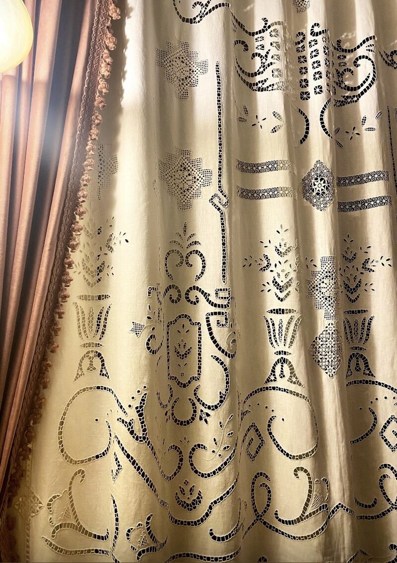 Close-up detail of cutwork embroidery with golden light shining through the openwork pattern