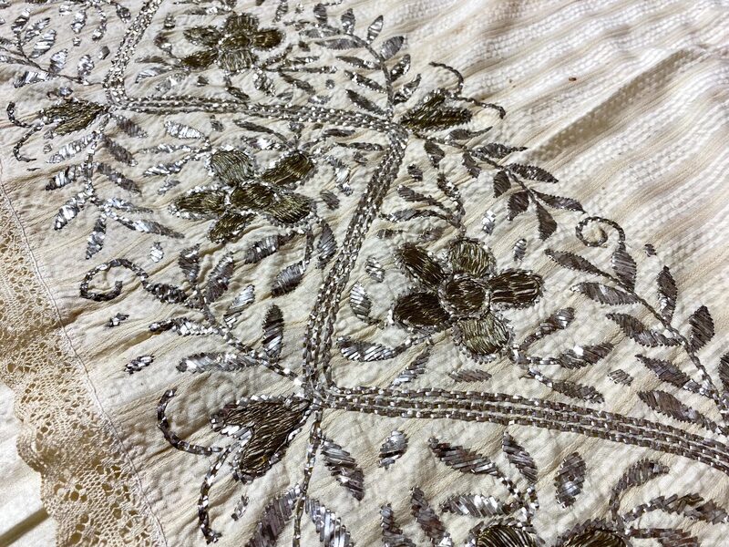 Antique silver and gold metal thread embroidery detail on aged fabric