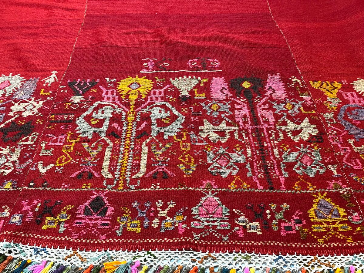Vintage Greek folk textile with colorful figural motifs on deep red ground